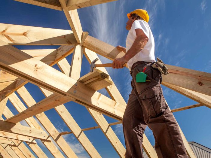 worker roofer builder working on roof structure on construction site